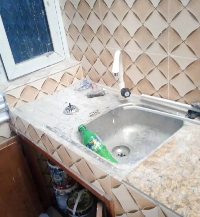 A kitchen sink covered in dust and debris