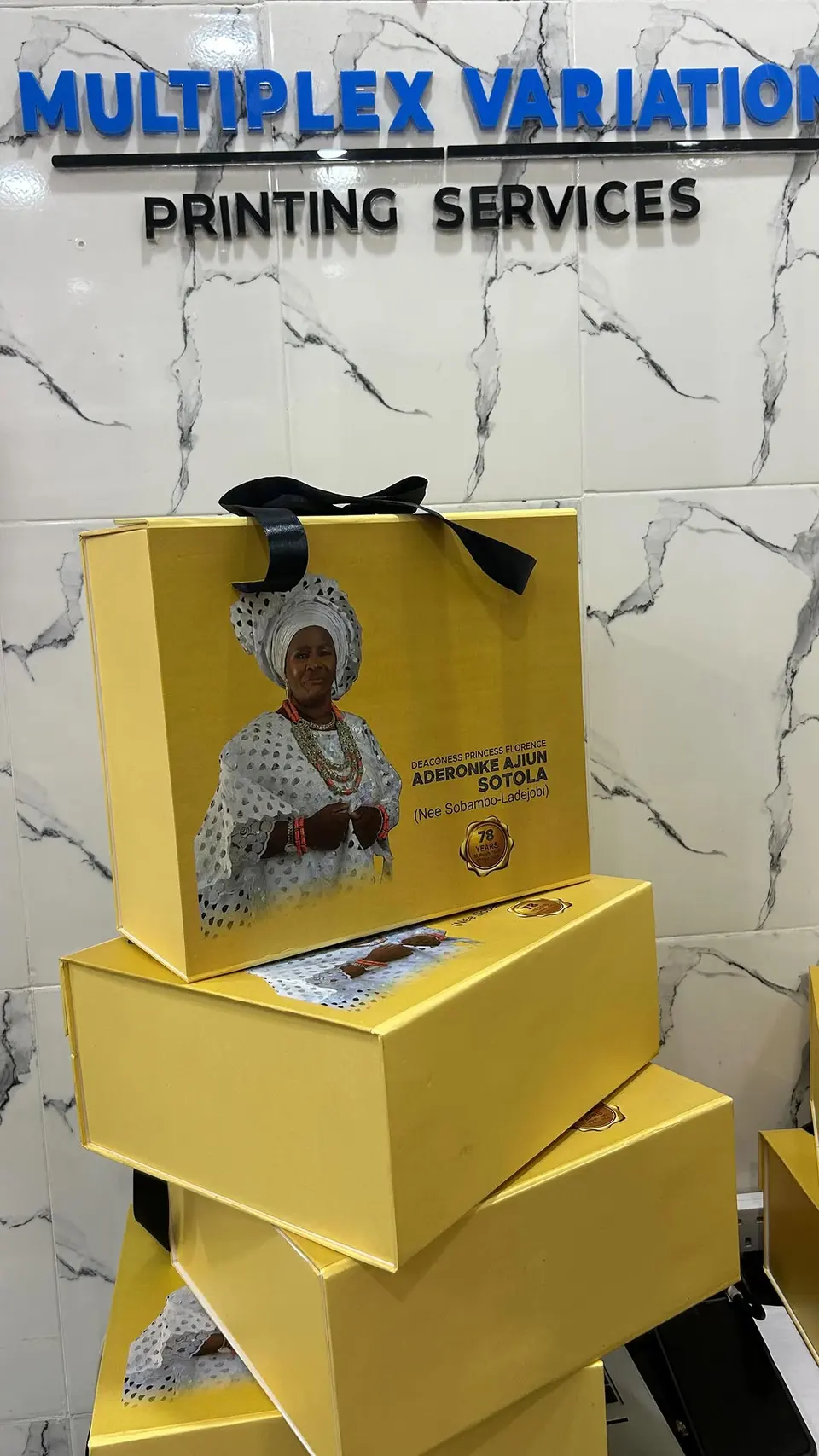 Yellow gift boxes and a printed gift bag in front of the Multiplex sign