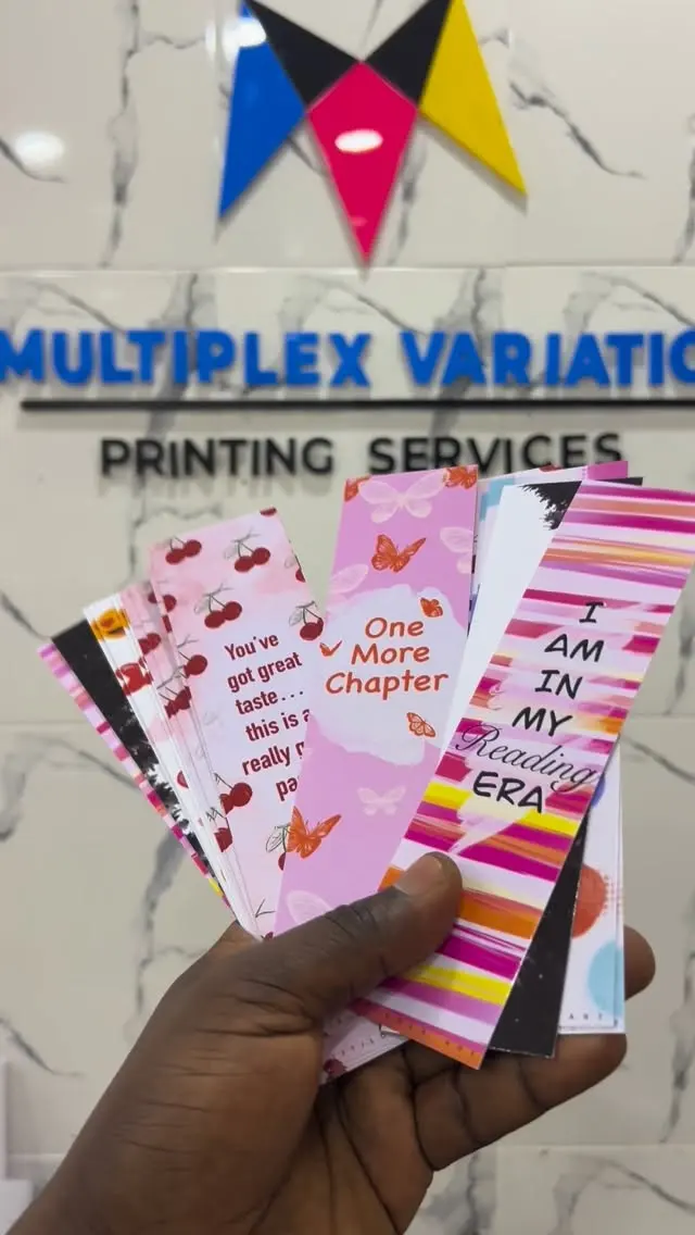 Printed bookmarks held in front of the Multiplex logo wall